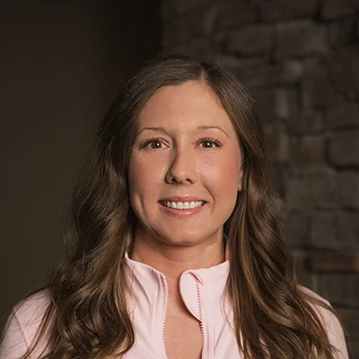 Office Manager Amanda Smiling In Front Of Blurred Wall